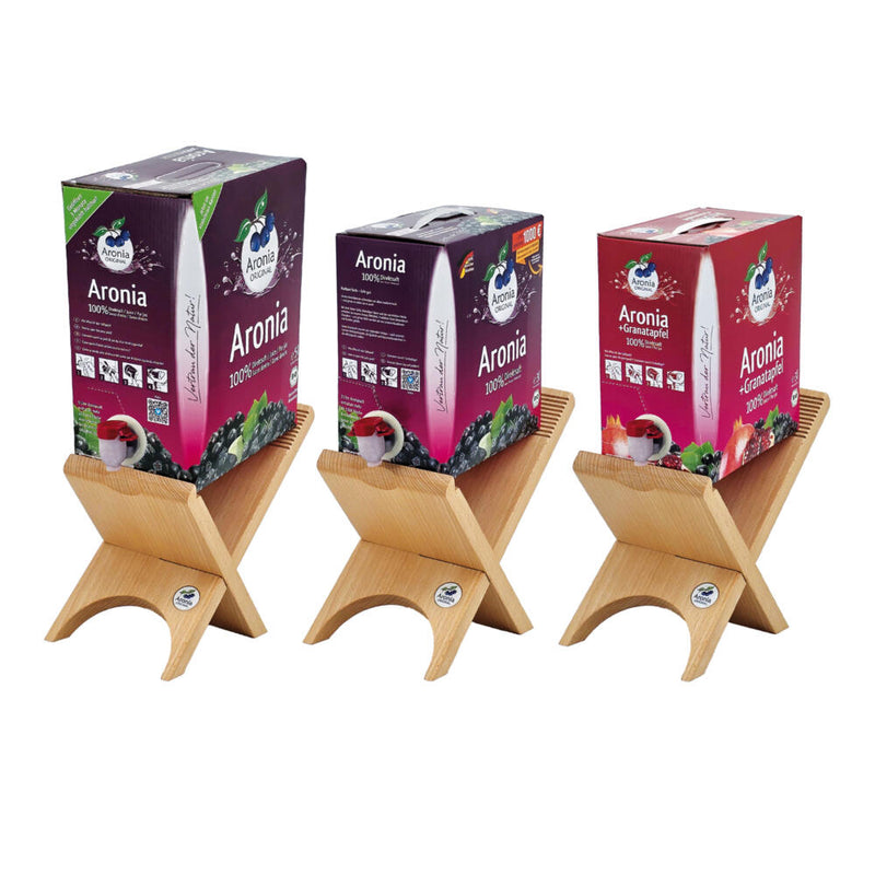 Drei Bag-in-Box-Kartons auf Holzständern nebeneinander: zwei Aronia, einer Aronia plus Granatapfel.
