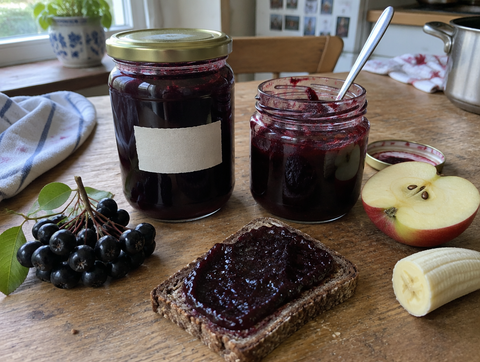 Aronia-apple-banana jam in a jar with bread and fresh aronia berries (symbolic image)