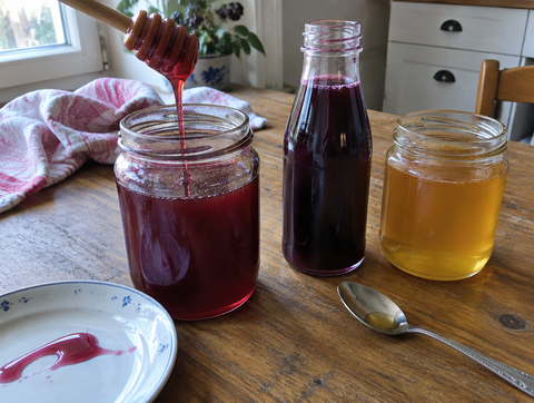 Aronia flower honey in a jar with honey spoon, next to aronia juice and flower honey (symbolic image)