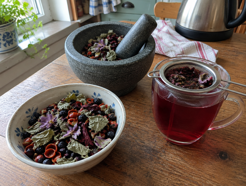 Herbal fruit tea blend with rosehip, aronia berries, raspberry leaves and flowers, plus a cup of tea (symbolic image)