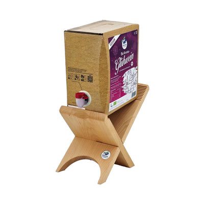 Bio-Aronia-Glühwein Bag-in-Box auf Holzständer, kraftbraune Box mit magentafarbenem Winterlabel und Vegan-Badge.